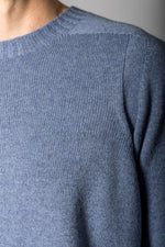 Close-up of embroidered logo and ribbed neckline on sky blue wool jumper