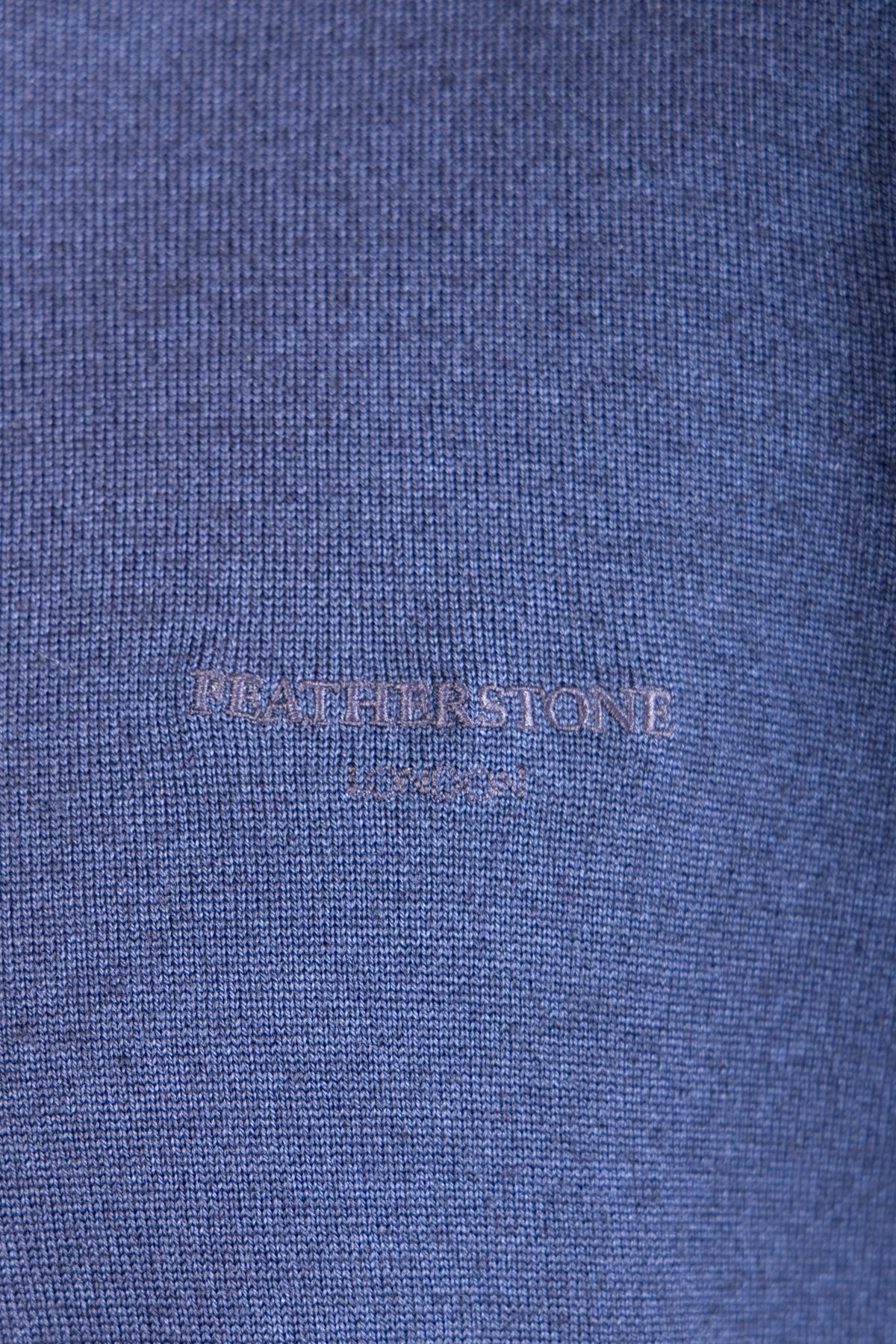Close-up of embroidered logo on navy wool crew neck jumper
