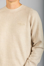Close-up of embroidered logo and marl knit texture on oatmeal wool jumper
